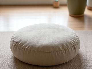 Comfortable, round meditation cushion in natural linen fabric on a light wooden floor.